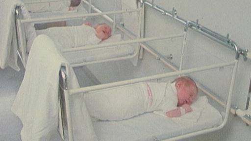 Zwei Neugeborene liegen in kleinen Betten auf der Babystation im Krankhaus.