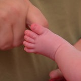 Eine Pflegemutter streichelt die Füße ihres kleinen Babys.