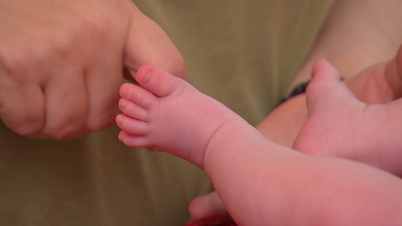 Eine Pflegemutter streichelt die Füße ihres kleinen Babys.