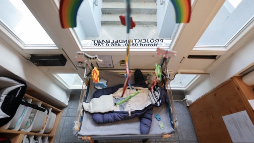 Eine Babyausstattung mit Schlafsack, Strampelanzug, Mütze und Kuscheltieren liegt in einem Wärmebett der Babyklappe im Kinderhaus Goethestraße in Hamburg-Altona