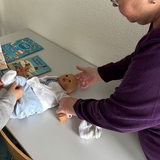 Eine Frau zeigt jungen Frauen an einer Puppe, wie ein Baby gewickelt wird