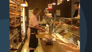 Eine Frau, die als Verkäuferin in einer Bäckerei arbeitet.