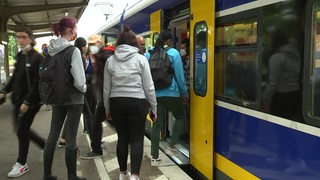 Einige Fahrgäste steigen am bahnhof gedrängt in einen Metronom-Zug. 