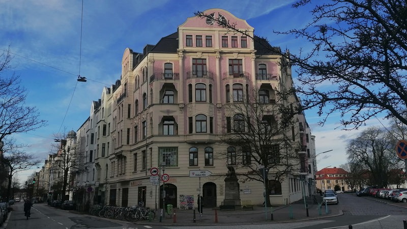 Blick auf ein rosa-weißes Gebäude an einer Straßenecke.