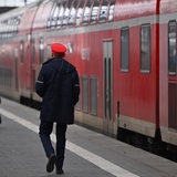 Bediensteter der Bahn geht auf dem Bahnsteig an einem Regionalzug entlang