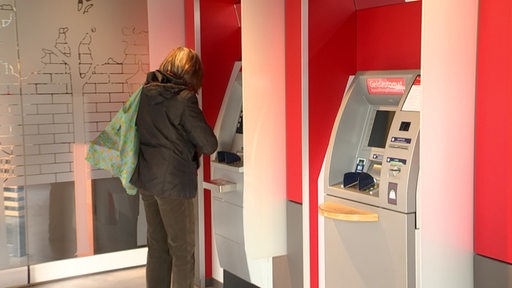 Ein Frau steht an einem Bankautomaten der Sparkasse.