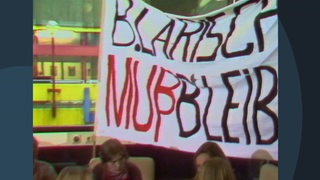 Menschen halten einen Banner auf dem steht "B. Larisch muß bleiben".