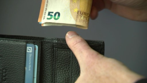 Eine Hand nimmt einen 50-Euro-Schein aus einem Portemonnaie.