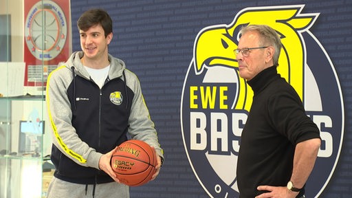 Der Trainer und der Geschäftsführer der Baskets Oldenburg mit einem Basketball in der Hand.