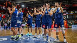 Die Basketballer der Eisbären Bremerhaven applaudieren gemeinsam den Fans in der Halle.