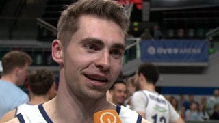 Basketball-Kapitän Adrian Breitlauch von den Eisbären Bremerhaven steht lächelnd in der Bremer Stadthalle nach dem Sieg gegen Jena beim Interview.