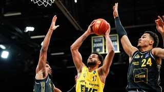 Norris Agbakoko springt mit einem Basketball in den Händen zum Korb hoch.