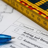 Auf einem Antrag auf Baugenehmigung liegt ein Maßstab und ein Kugelschreiber.