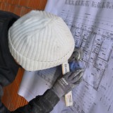 Ein Bauarbeiter schaut auf einen Bauplan und notiert etwas.