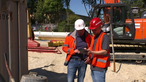 Bauarbeiter- und Leiter der Firma Syniotec auf einer Baustelle.