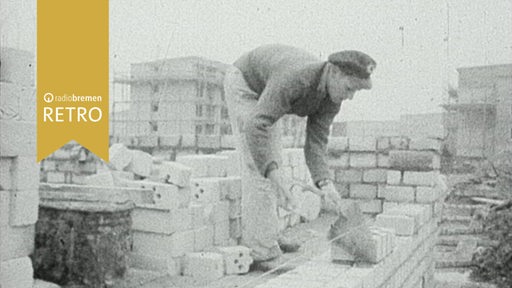 Bauarbeiter mauert auf einer Baustelle mit anderen Hochbauten