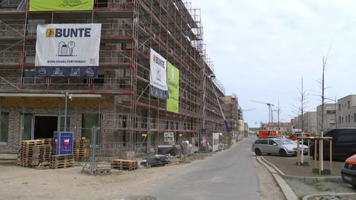 Ein Gebäuderohbau neben dem eine Baustraße verläuft.