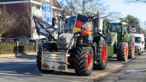 Zwei Traktoren stehen an einer Straße in Bremen. Auf dem vorderen ist eine Flagge der Landvolk-Bewegung zu sehen.