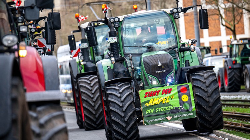 Zahlreiche Traktoren stehen in der Bremer Überseestadt bei einer Demonstration von Bauern. Auf einem Schild ist dabei die Aufschrift "Zieht der "Ampel" den Stecker" zu lesen.