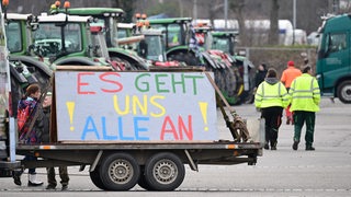 Mit Traktoren und einem Transparent mit der Aufschrift: "Es geht und alle an" demonstrieren ein Landwirte mit Traktoren