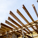 Eine Holzkonstruktion für den Bau einer weiteren Etage aus Stahlbeton steht auf einer Baustelle.