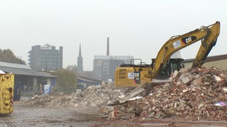 Eine Baustelle, bei der ein gelber Kran den Bauschutt bewegt.