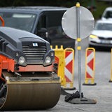 Straßenbaustelle mit Absperrungen und einer Asphaltierungsraupe im Vordergrund