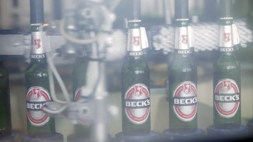 Mehrere Becks-Bierflaschen stehen nebeneinander bei der Produktion.