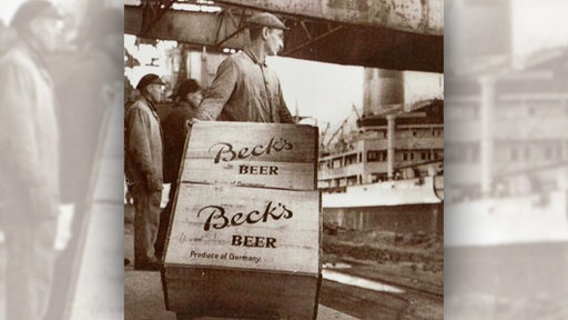Historische Aufnahme zeigt einen Hafenarbeiter, der Kisten mit "Beck's Beer" verlädt