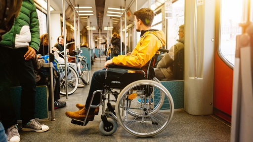 Ein junger Mann im Rollstuhl in einer S-Bahn.