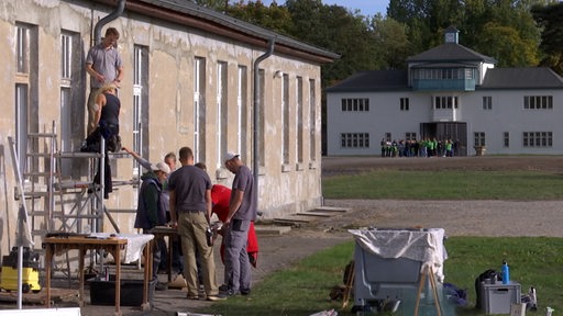 Bremer Berufsschülerinnen und Berufsschüler renovieren eine Fassade der Gedenkstätte Sachsenhausen.