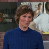 Eine Frau im blauen Pullover steht in einem Fernsehstudio