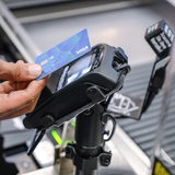 Ein Mann hält eine Bezahlkarte an ein EC-Terminal in einem Supermarkt