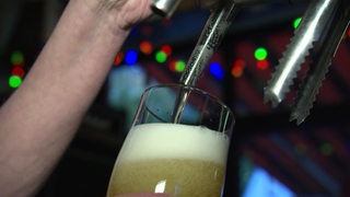 Ein Bierglas wird mit Bier aus einem Zapfhahn befüllt.
