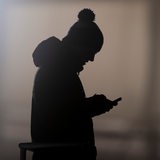 Ein Mann schaut auf ein Smartphone und zeichnet sich als Silhouette ab.