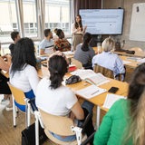 Teilnehmerinnen und Teilnehmer eines berufsbezogenen Sprachkurses  sitzen während dem Unterricht in einem Kursraum