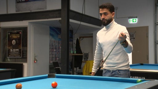 Der Billardspieler Mohammad Soufi steht mit einem Queue in der hand hinter einem Billardtisch.