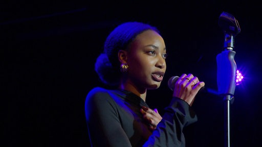Eine schwarze Sängerin steht auf der Bühne.