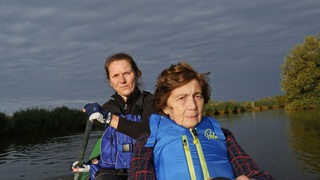 Eine ältere Frau und eine jüngere sitzen in einem Kanu