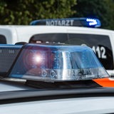 Ein Polizeiwagen steht vor einem Notarztwagen.