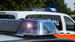 Ein Polizeiwagen steht vor einem Notarztwagen.