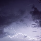 Ein Blitz zieht sich über einen dunklen, wolkenverhangenen Himmel.