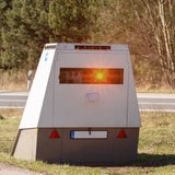 Ein Blitzer für Autos steht auf einem Grünstreifen.