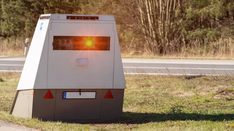 Ein Blitzer für Autos steht auf einem Grünstreifen.