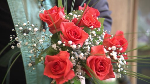 Es ist ein Blumenstrauß aus Rosen und Schleierkraut zu sehen.