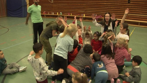 Eine Gruppe Kinder tobt in der Turnhalle es Blumenthaler TV bei einem Spiel auf dem grünen Hallenboden herum.