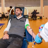 Ein Mann auf einem bequemen Stuhl sitzend beim Blutspenden in einem Zentrum neben einer Krankenschwester in Uniform. 