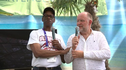 Frank Scheffka und Olympiasieger Bob Beamon gemeinsam mit Mikrofon auf der Bühne in Delmenhorst.