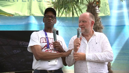 Frank Scheffka und Olympiasieger Bob Beamon gemeinsam mit Mikrofon auf der Bühne in Delmenhorst.