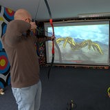 Ein Mann zielt mit einem Bogen auf eine Leinwand.